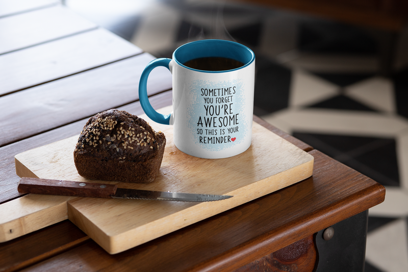 “Sometimes you forget you're awesome” mug with blue handle, placed on a wooden cutting board with a slice of bread.