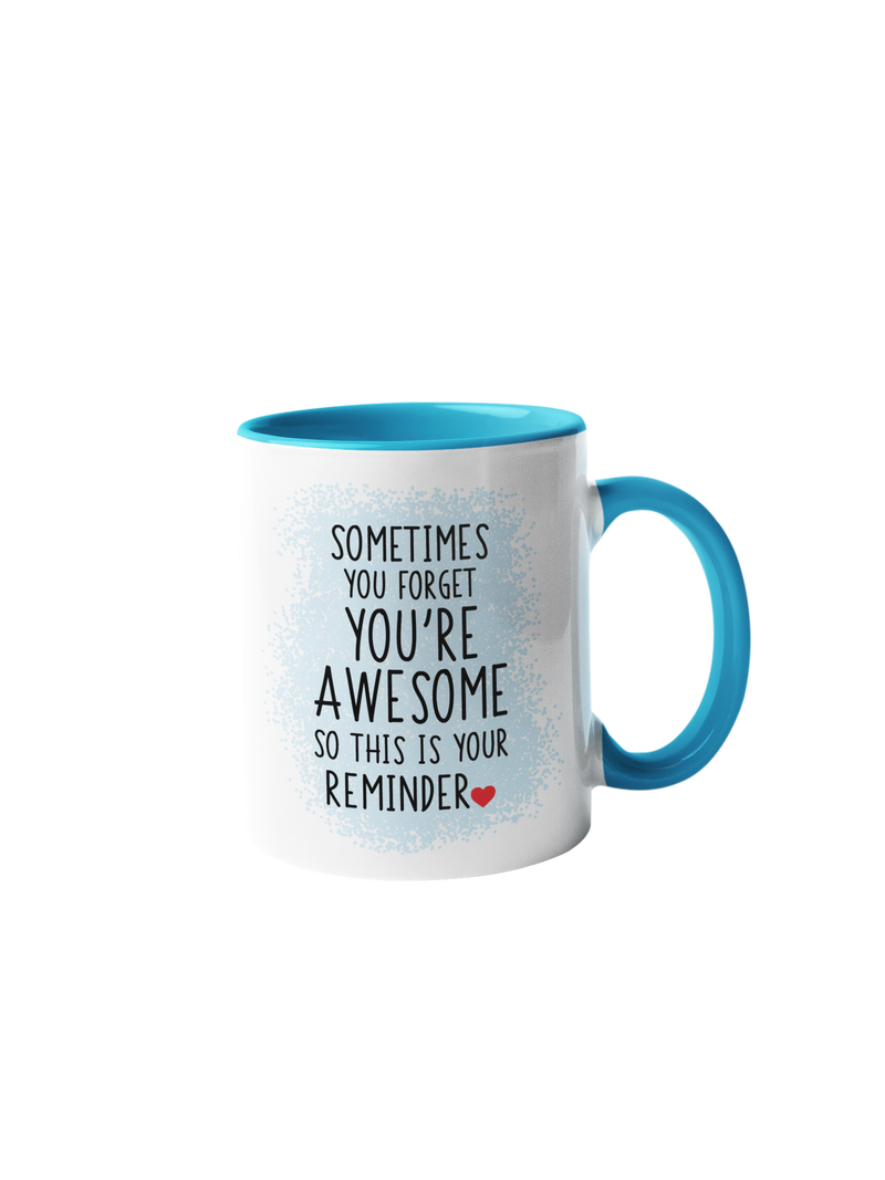 “Sometimes you forget you're awesome” coffee mug with a white body and blue handle, featuring black text and a red heart.
