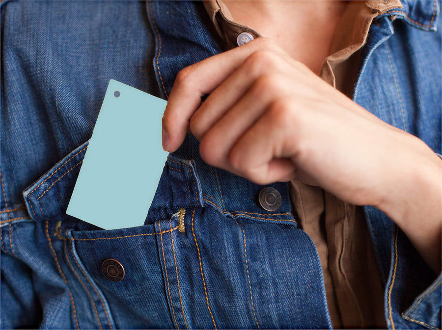 Blank blue index card, 2” x 3.5”, hole-punched, being held in a hand near a denim jacket pocket.