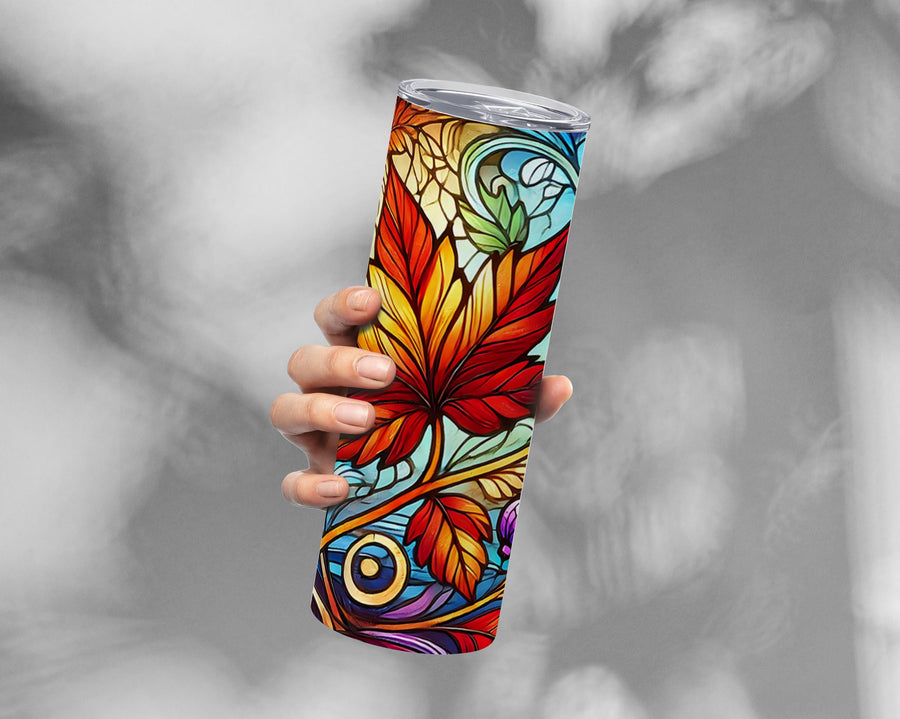 Autumn stained glass tumbler featuring fall leaves and berry design in vibrant colors, held in a hand.